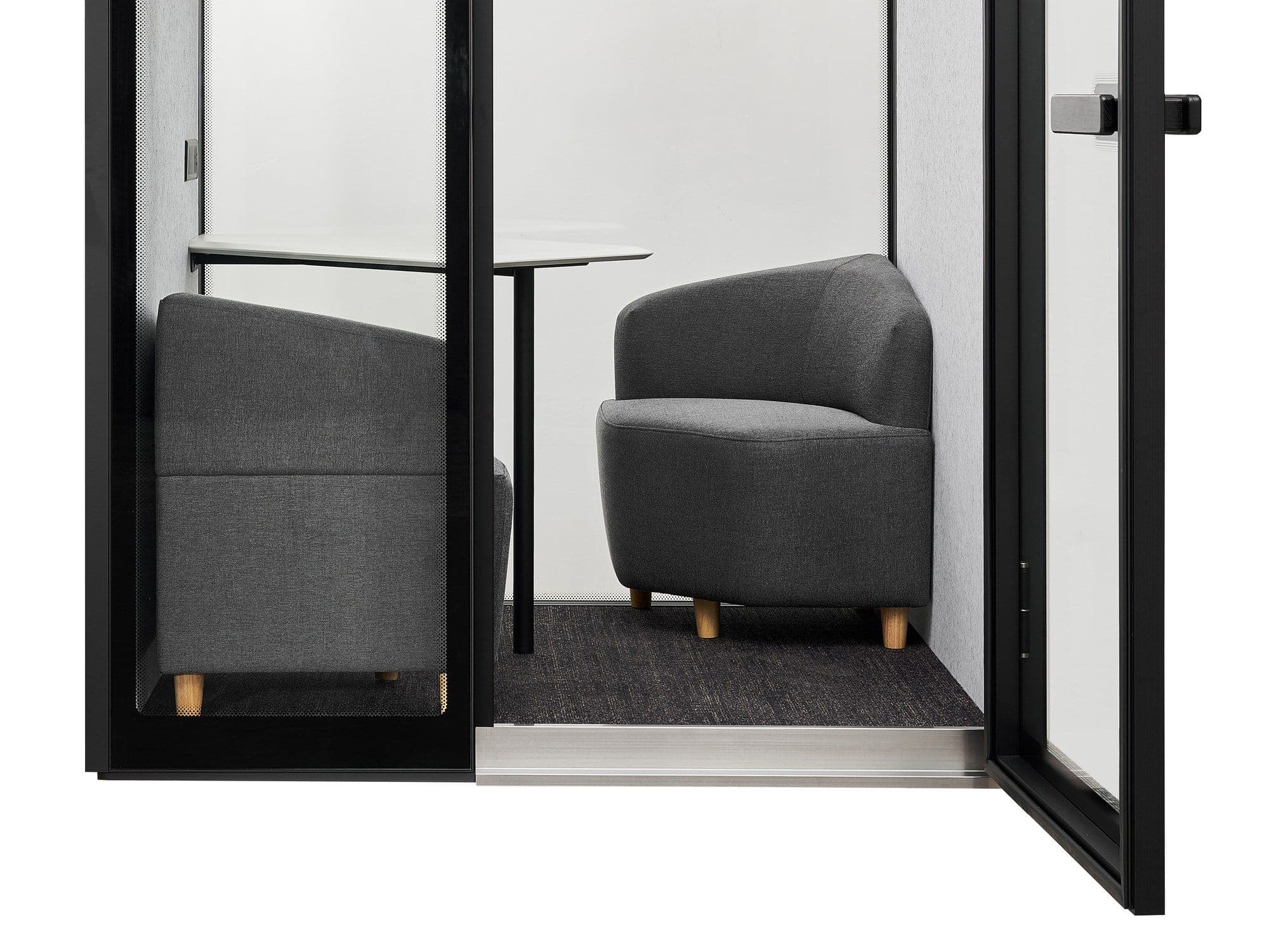 Inside an M2-Pod through the open door — two grey upholstered sofa chairs either side of a round white table